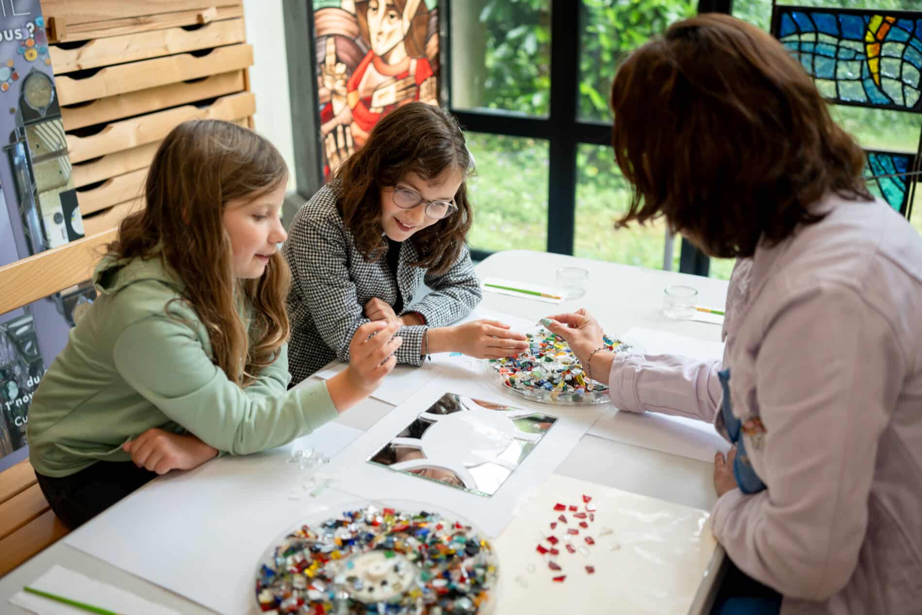 Famille créant son propre miroir avec des morceaux de verre de toutes les couleurs